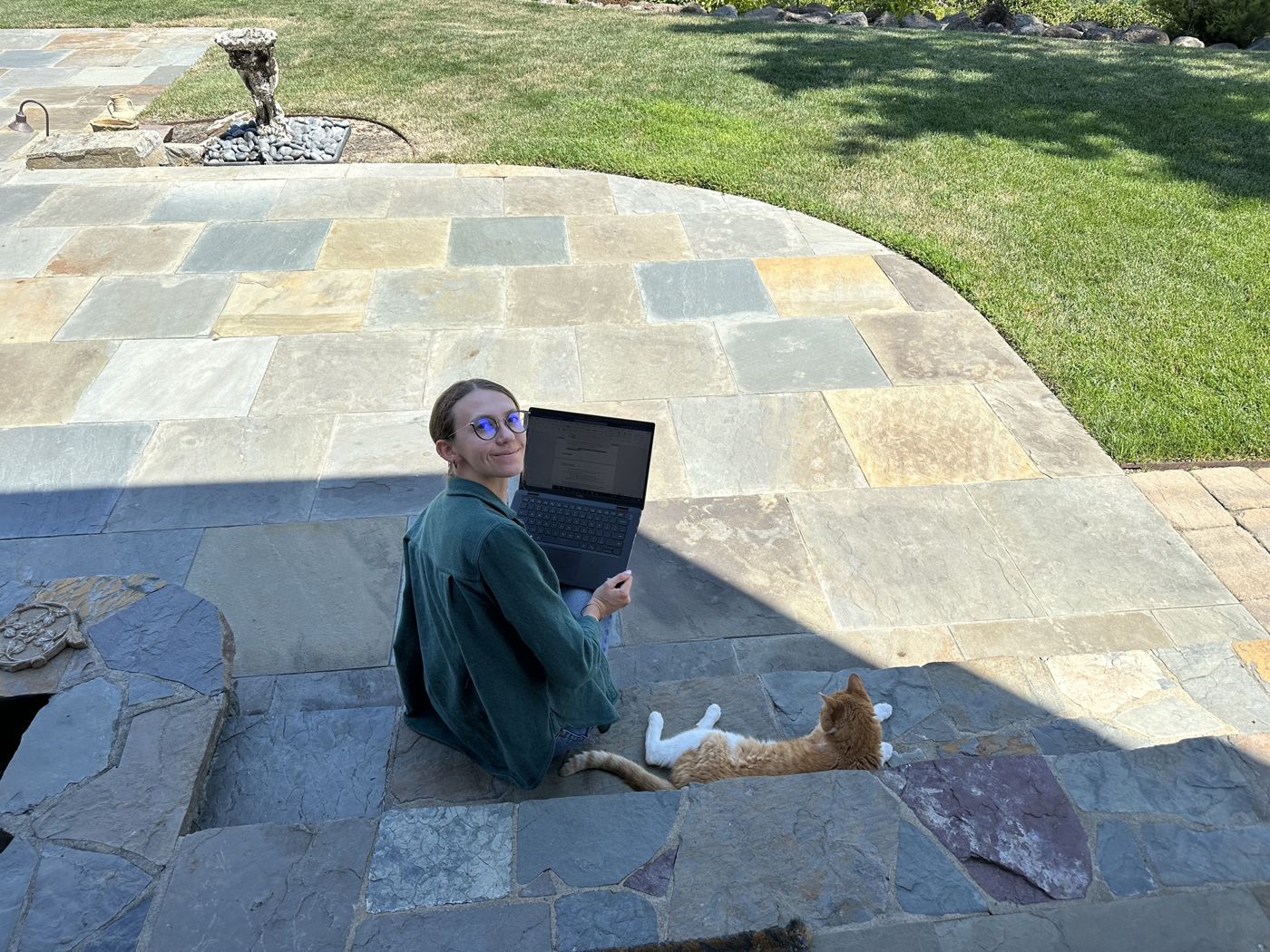 Danika on a laptop outside with a cat